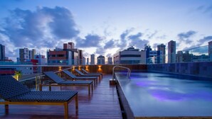 Una piscina al terrat amb gandules i vista a la ciutat.