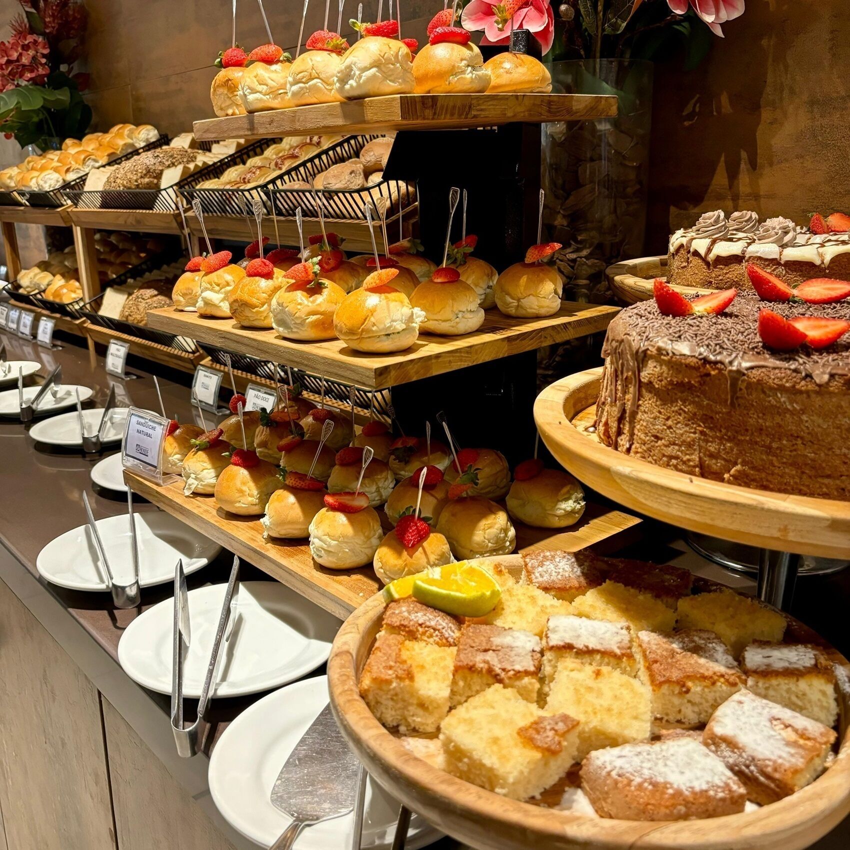 A buffet with various baked goods, including bread rolls, pastries, and a cake.