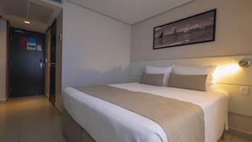 Ein Hotelzimmer mit einem großen Bett, einem Kopfteil, einem Wandbild und einer Tür mit einem Schild.
