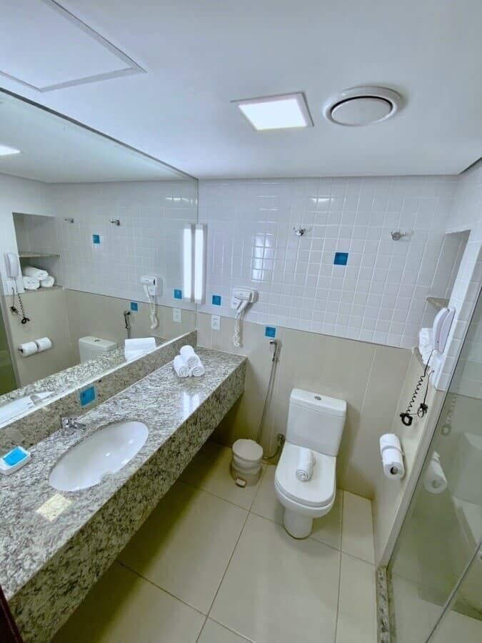 A bathroom with a granite countertop sink, a toilet, and a glass shower enclosure.