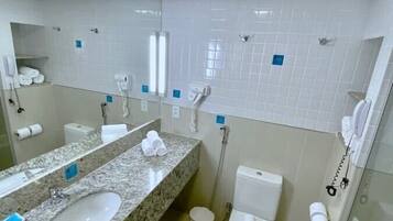 A bathroom with a granite countertop sink, a toilet, and a glass shower enclosure.