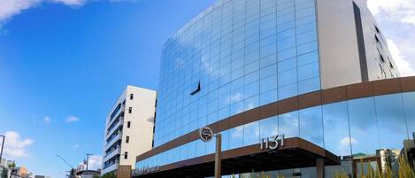 A modern hotel with a glass facade, a covered entrance, and a visible address number 131.