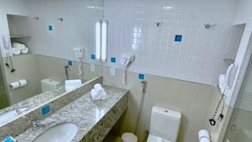 A modern bathroom with a granite countertop, a white sink, a toilet, and a glass shower enclosure.