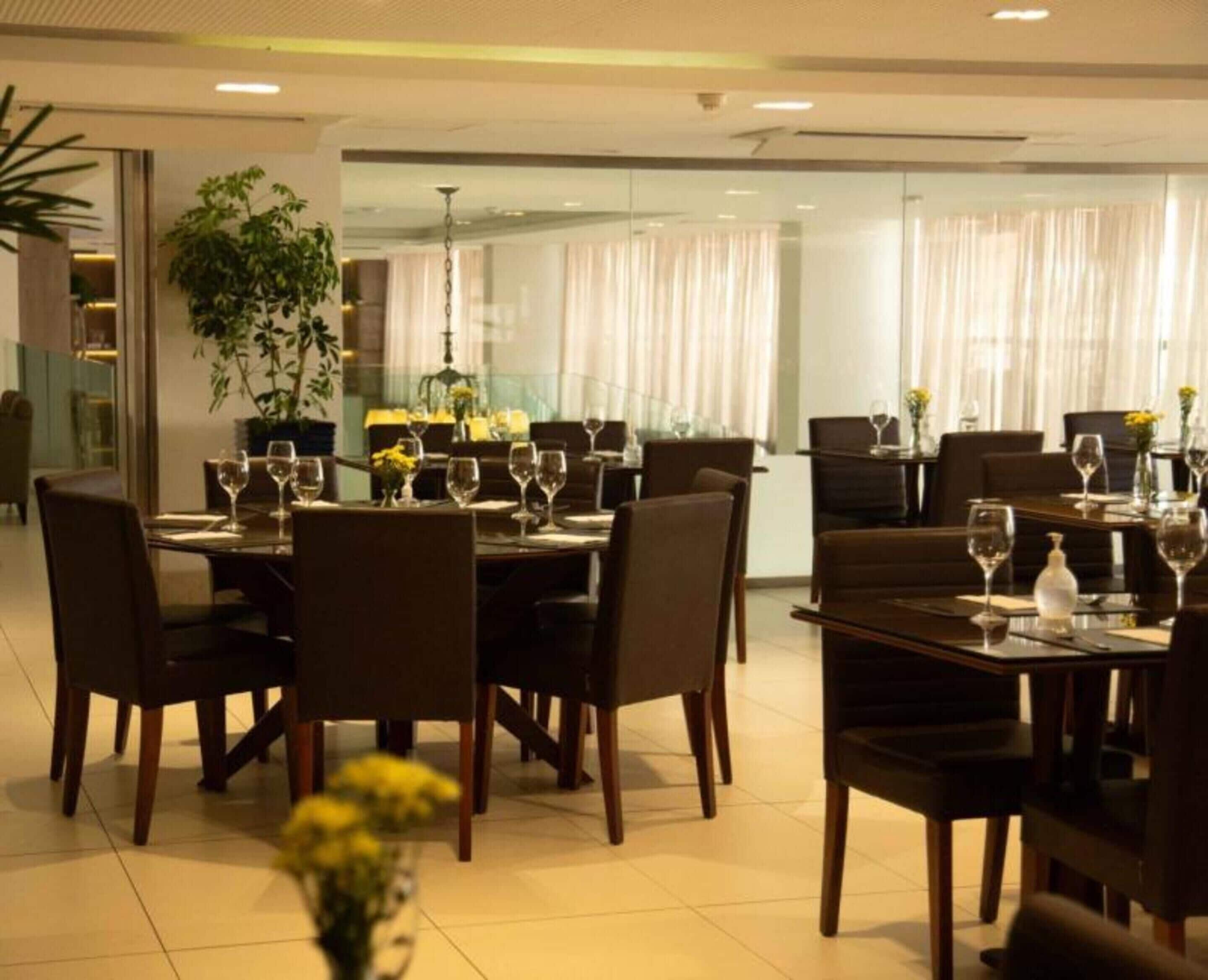 Un restaurante con varias mesas dispuestas para comer, con sillas y copas de vino.