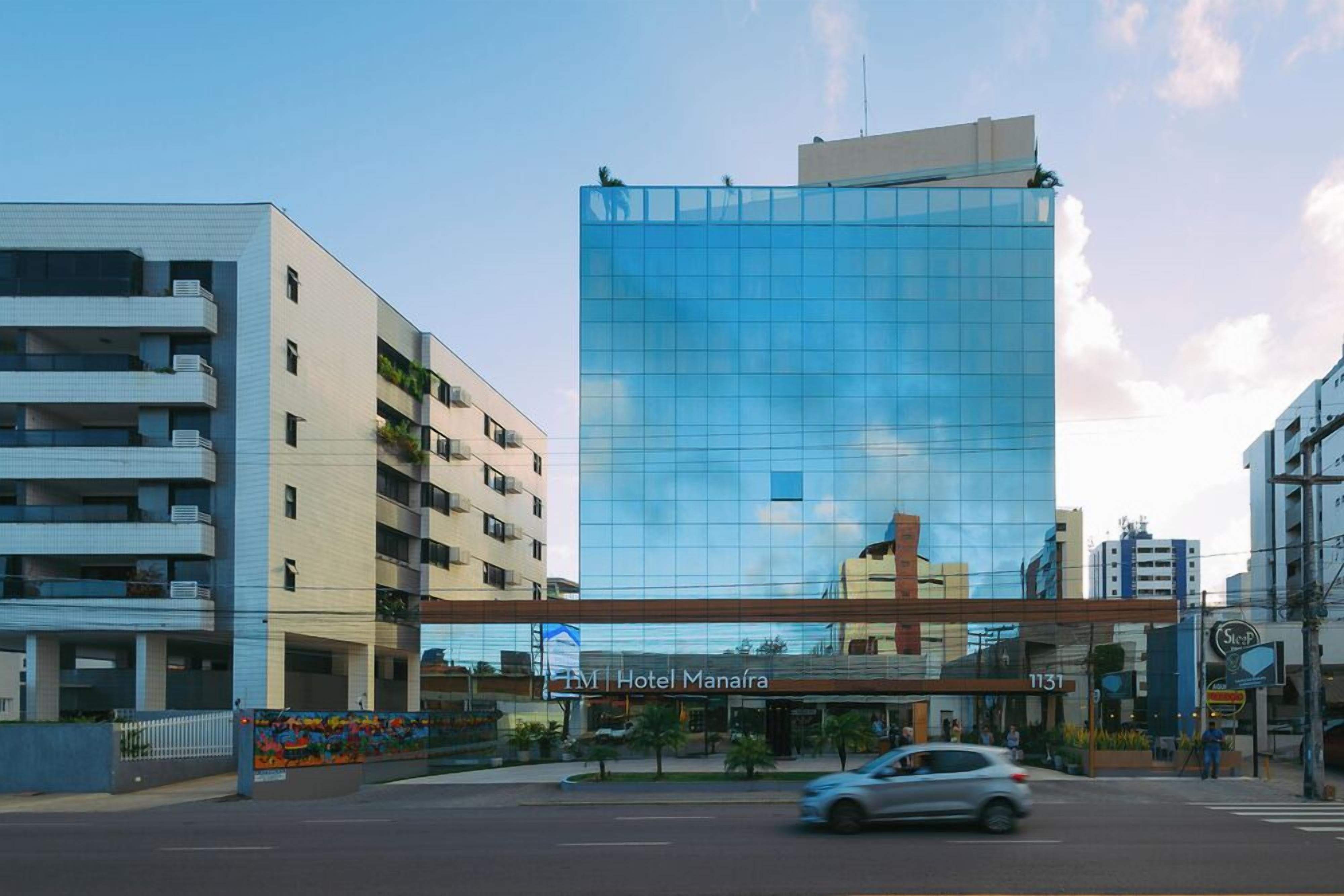 Ein modernes Hotel mit Glasfassade, mehreren Etagen und einem markanten Eingang.