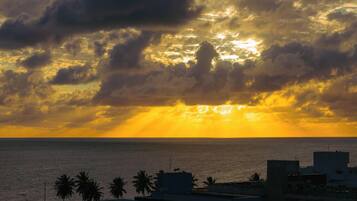 A coastal sunset with buildings and palm trees in the foreground.