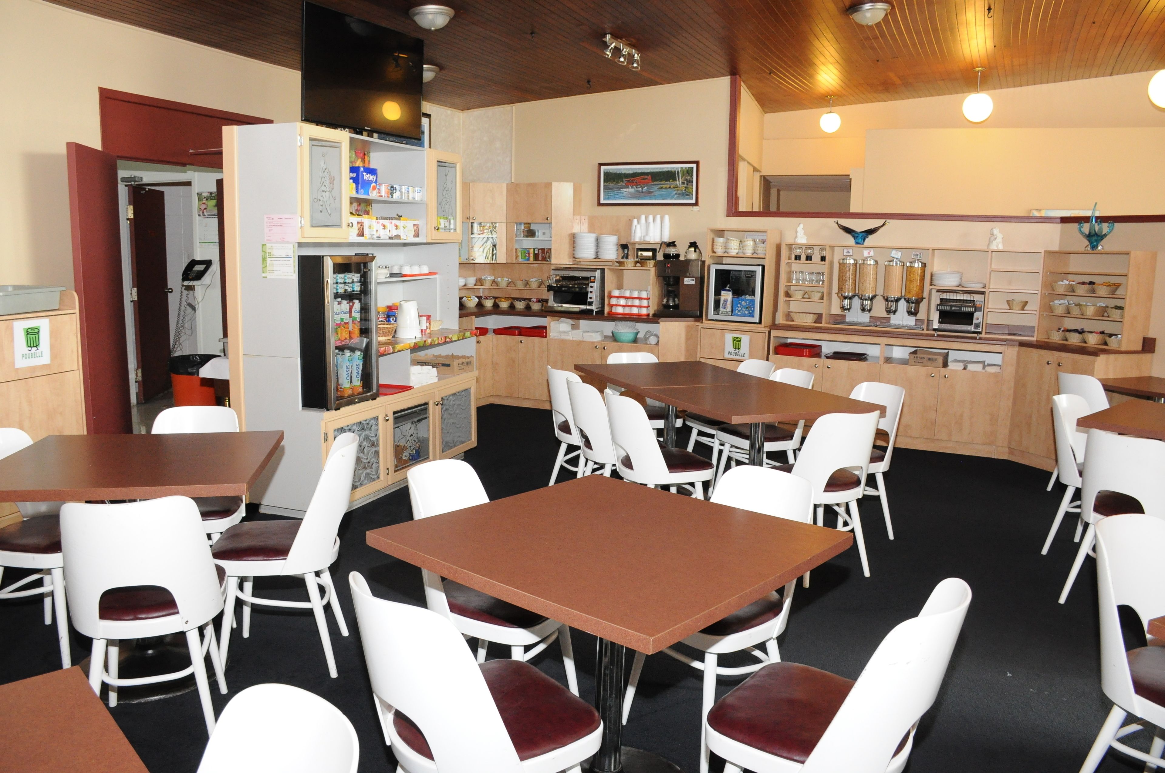 A dining area with multiple tables and chairs, a refrigerator, a coffee machine, and a microwave.