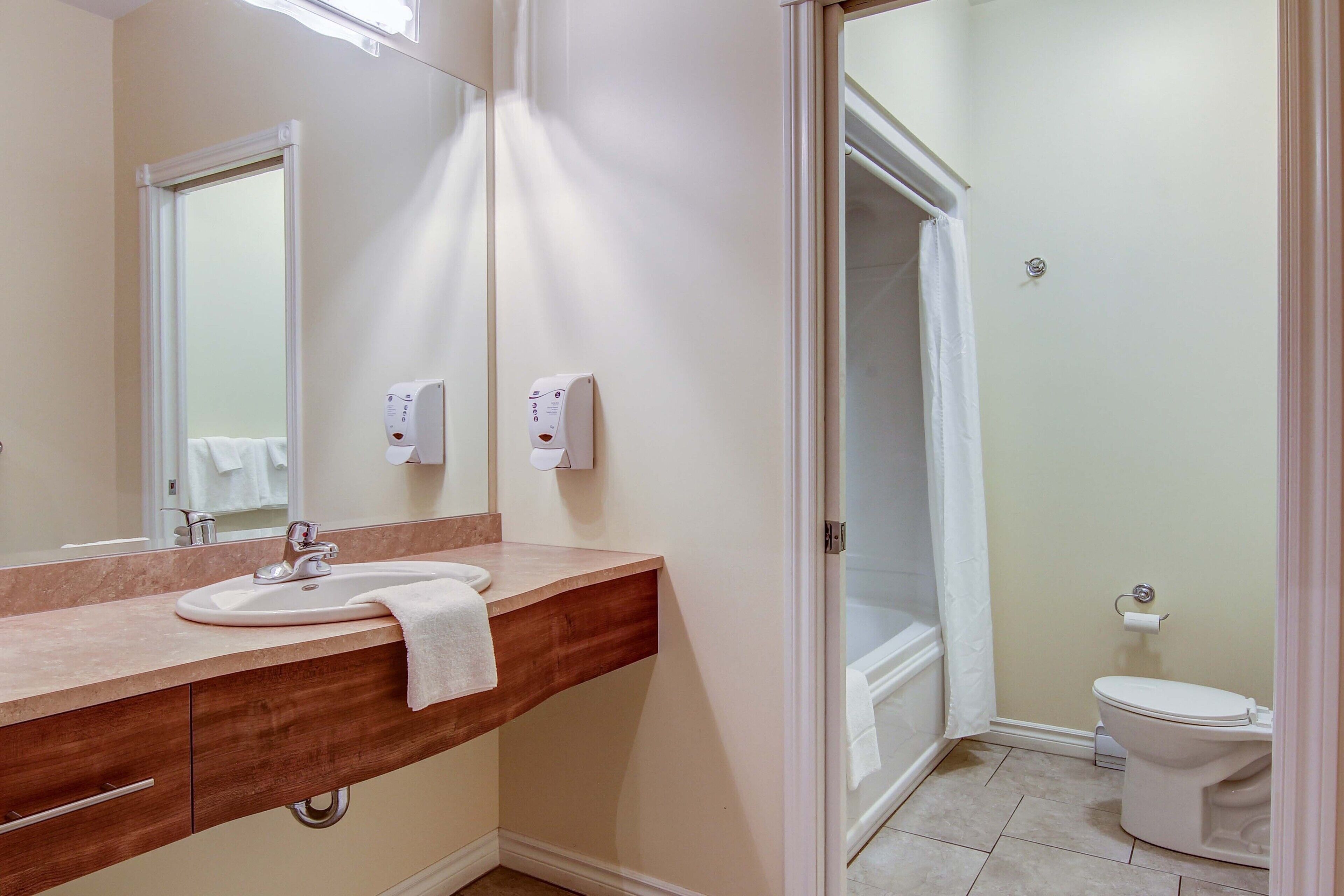 Une salle de bain équipée d’un lavabo, d’un miroir, d’une serviette, de toilettes et d’une douche.