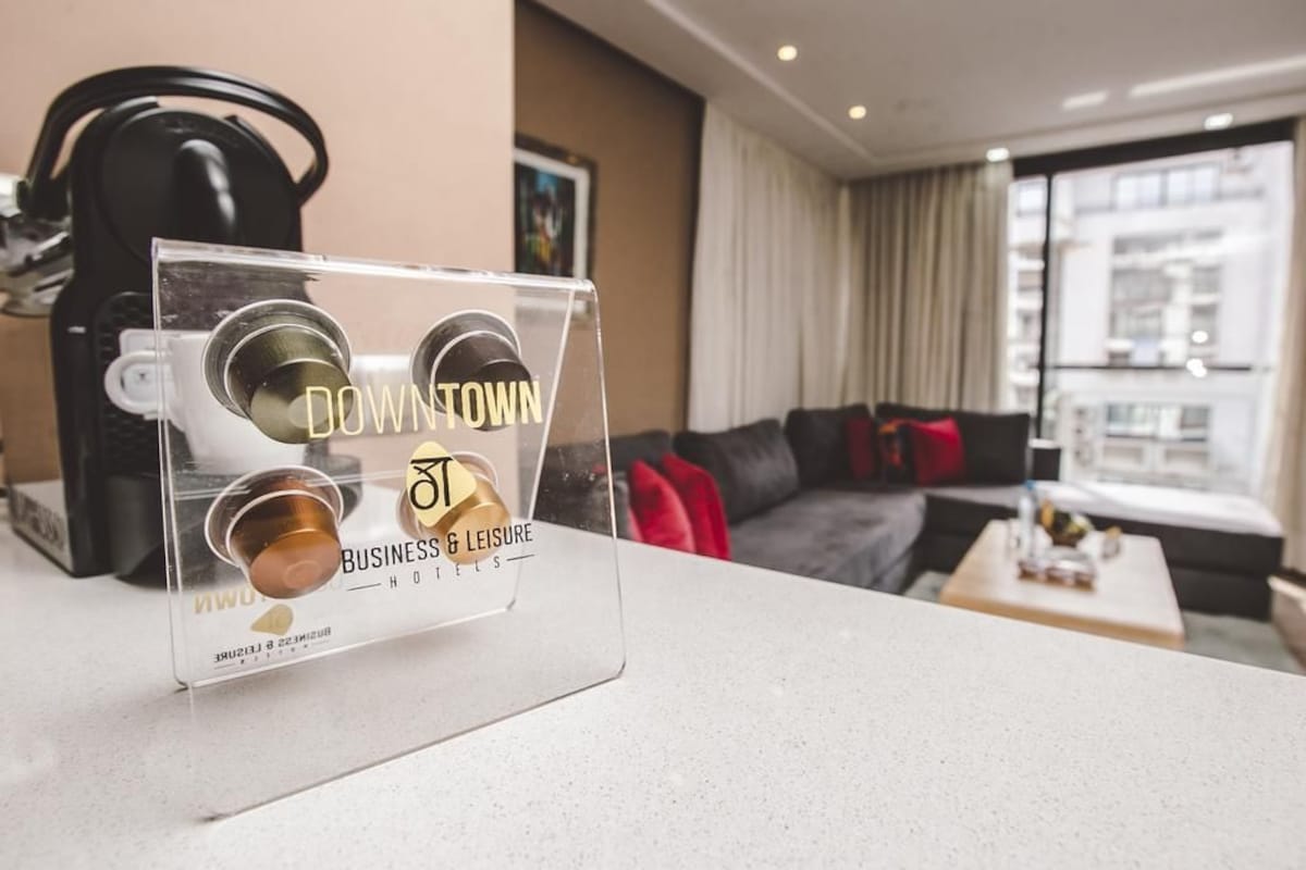 A clear acrylic stand with three coffee cups labeled "Downtown Business & Leisure Hotels" in a modern hotel room.