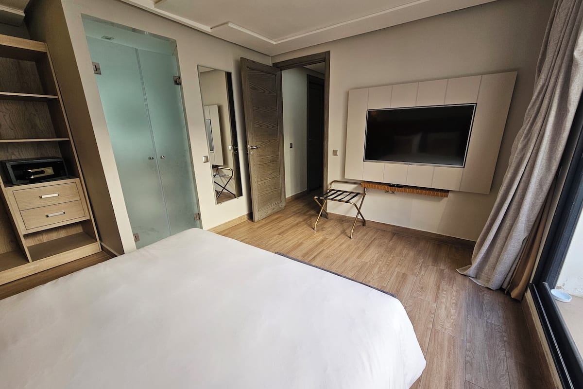 Ein Hotelzimmer mit Bett, Schrank, Spiegel, Fernseher und einem kleinen Tisch.