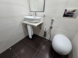 Un baño con lavamanos blanco, inodoro, espejo y toallero.