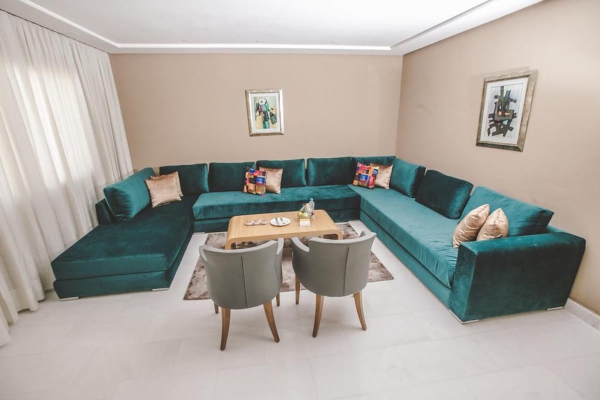 A living room with a sectional sofa, two armchairs, a coffee table, and two framed artworks on the walls.