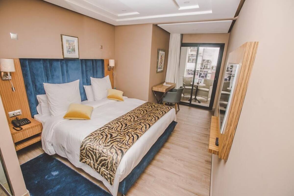 Ein Hotelzimmer mit einem großen Bett, einem Schreibtisch und Blick auf die Stadt durch das Fenster.