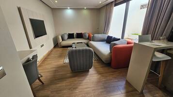 A modern living room with a sofa, ottoman, and a desk with a laptop.