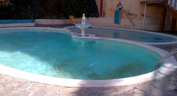 A swimming pool with a central fountain, surrounded by stone tiles. - Torola Hotel & Beach Resort (La Union)