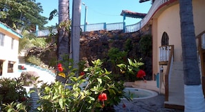 A courtyard with a pool, palm trees, and a staircase leading to a building with a blue railing. - Torola Hotel & Beach Resort (La Union)