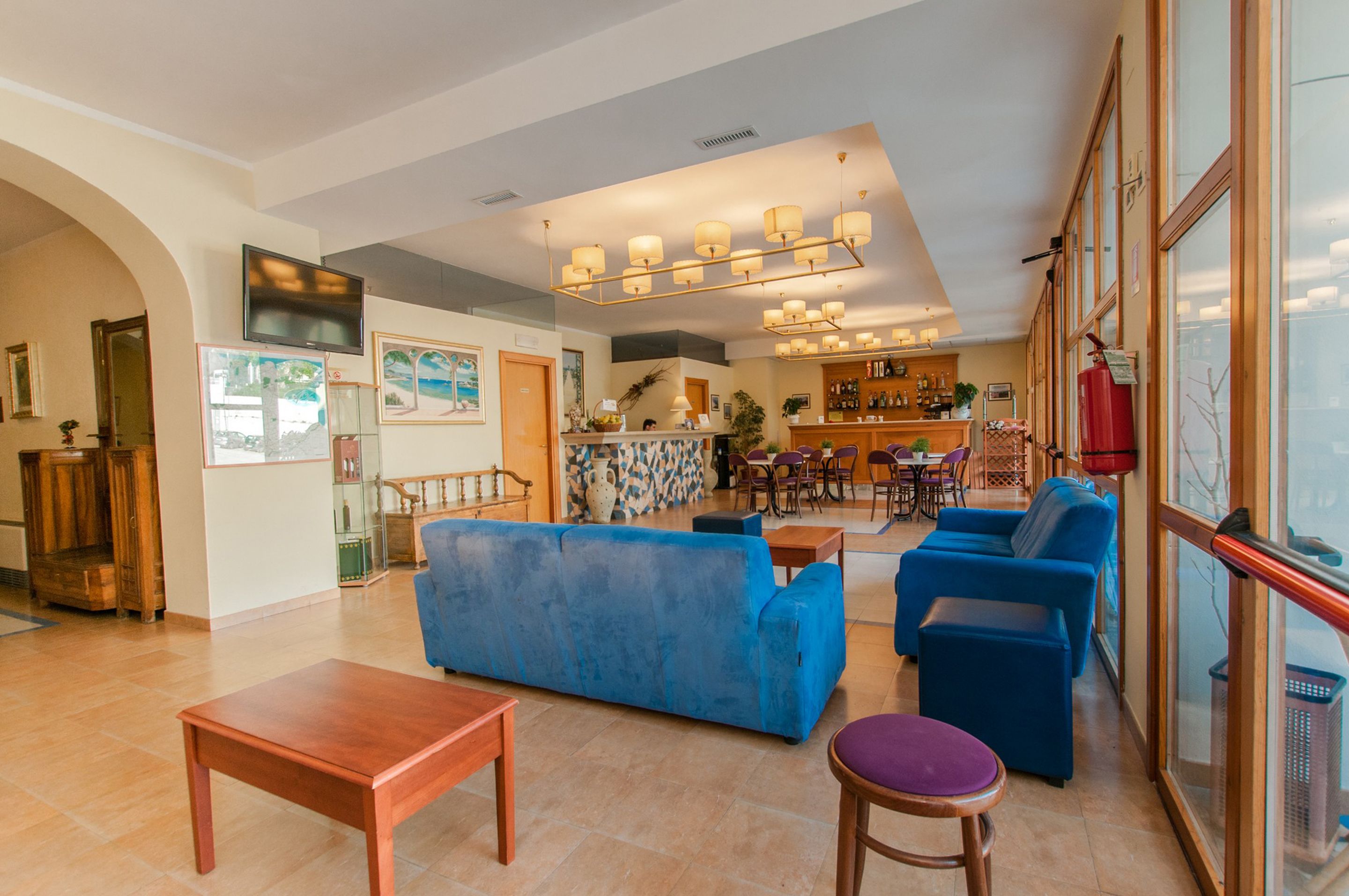 A spacious living area with a blue sofa, wooden coffee table, and a bar area in the background.