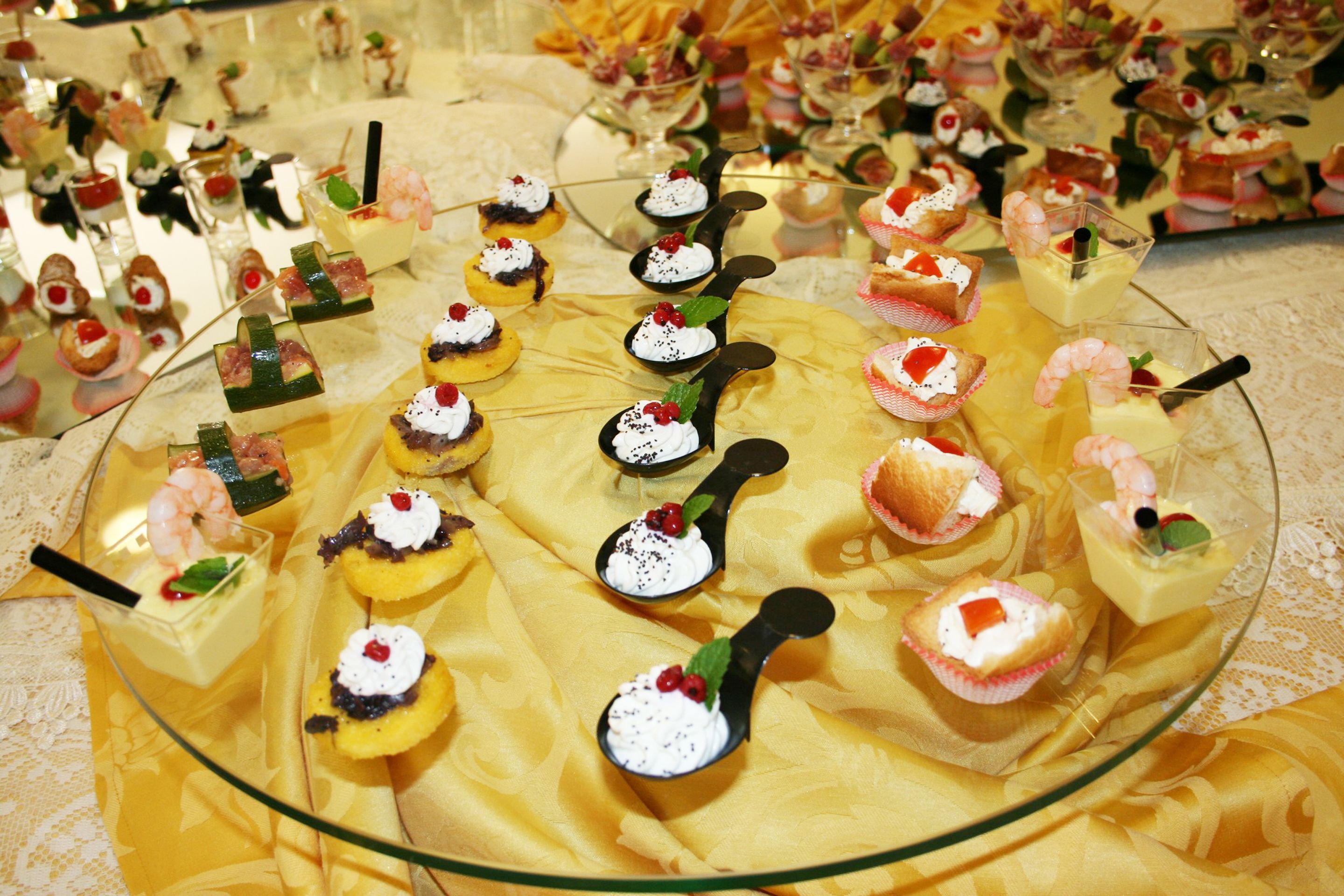 A variety of desserts on a glass platter, including cupcakes, macarons, and other sweet treats.