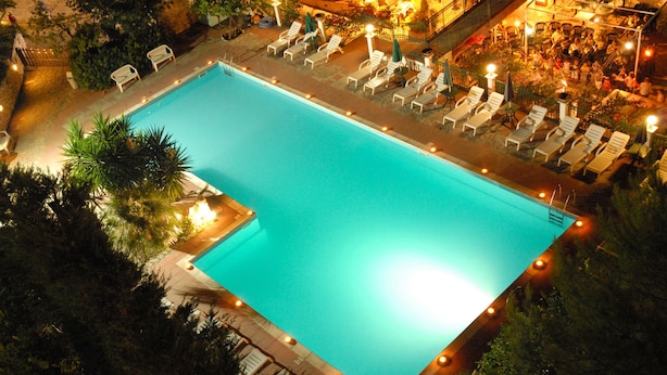 A rectangular swimming pool with a tiled deck, surrounded by lounge chairs and umbrellas. - Park Hotel Villa Americana (Rodi Garganico)