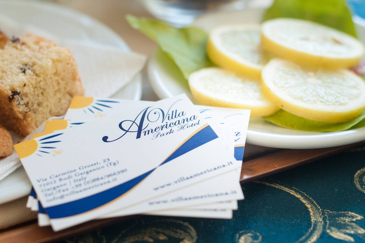 A business card for Villa Americana Park Hotel, a muffin, and lemon slices on a plate.