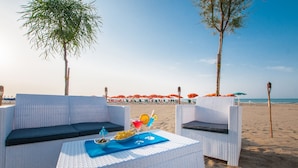 A beachside lounge with white wicker furniture and a table set with drinks and fruits. - Park Hotel Villa Americana (Rodi Garganico)