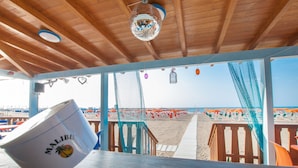 A beachside restaurant with a wooden deck, a view of the beach, and a Malibu logo on a white bowl. - Park Hotel Villa Americana (Rodi Garganico)