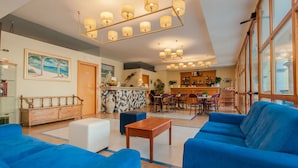 A spacious lobby with blue sofas, a wooden bench, and a tiled coffee bar area. - Park Hotel Villa Americana (Rodi Garganico)