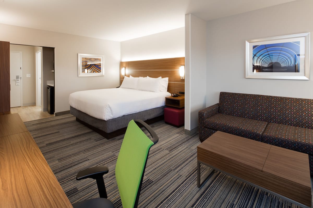Une chambre d’hôtel avec un lit, un canapé, un bureau et une chaise.