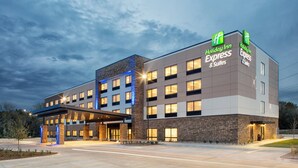 Un hôtel Holiday Inn Express & Suites au design moderne, avec une façade combinant briques et pierres, plusieurs entrées et une enseigne lumineuse.