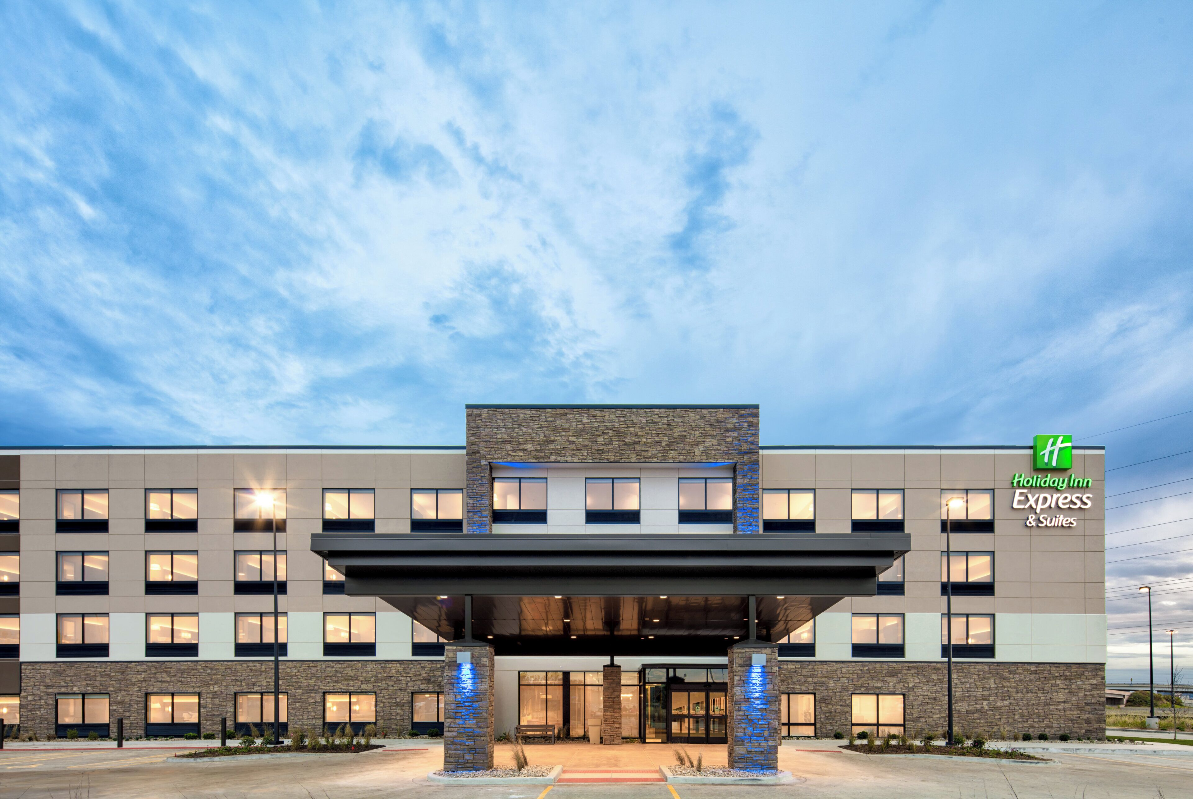 Edificio de Holiday Inn Express & Suites con un diseño arquitectónico moderno, que presenta un techo plano, ventanas amplias y una entrada destacada.