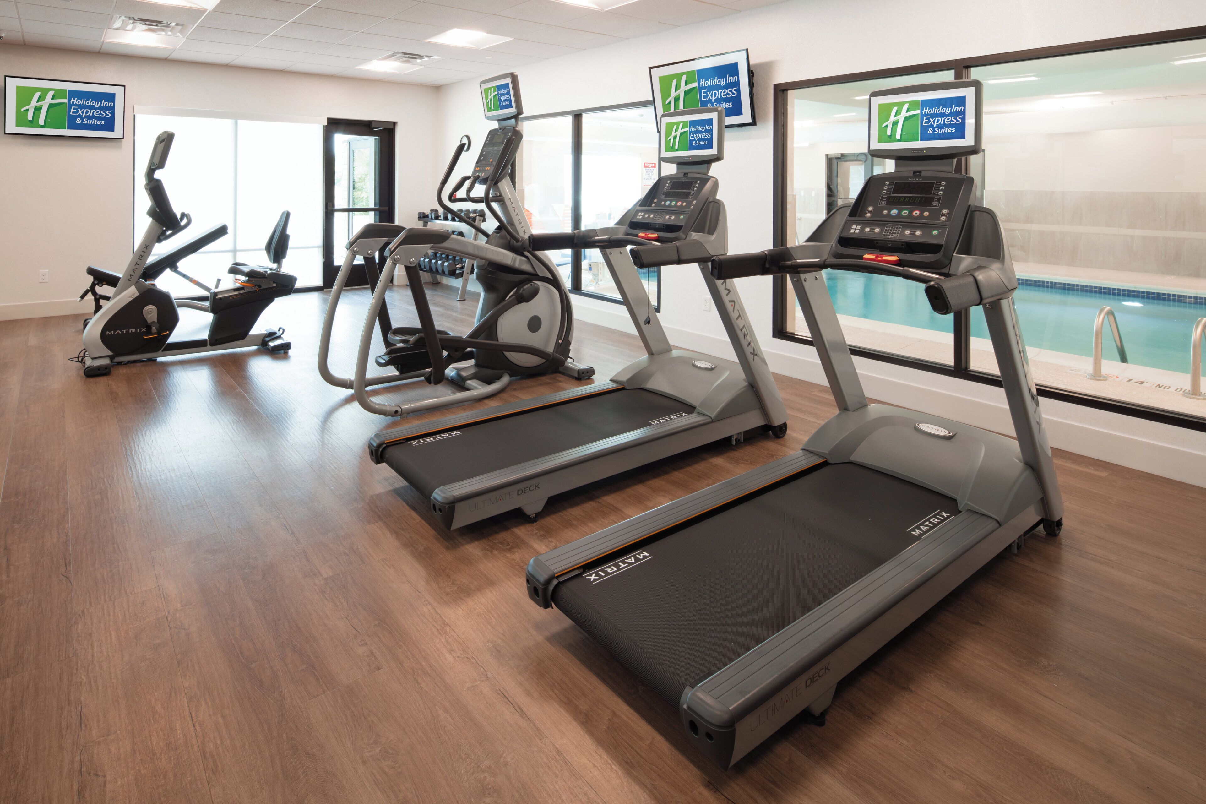 A fitness center with treadmills, elliptical machines, and a pool.
