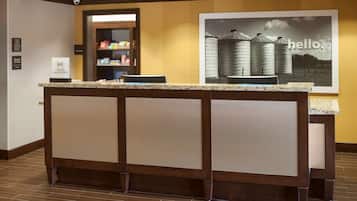 A reception area with a counter, a framed picture on the wall, and a shelf with snacks.