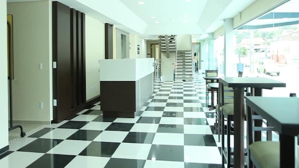 A hotel lobby with a checkered floor, a staircase, and a reception desk. - Hotel Sollievo (Irati)