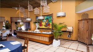Un restaurante con un mostrador central, lámparas en forma de jaula de pájaros colgantes, un cuadro grande y armarios de madera.