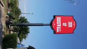 A red sign with white text reading "ROCKWALL OF INN" against a clear blue sky. - Inn of Rockwall (Rockwall)