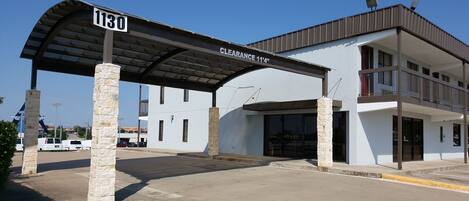 A building with a covered entrance, stone pillars, and a sign indicating a clearance height of 11'4".