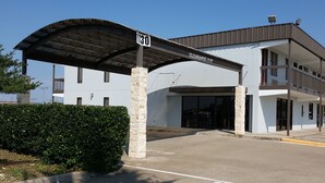A building with a covered entrance, stone pillars, and a sign indicating a clearance of 11'4". - Inn of Rockwall (Rockwall)