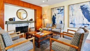 A living room with a fireplace, wooden paneling, and abstract paintings. - Waters Edge Hotel (Tiburon)