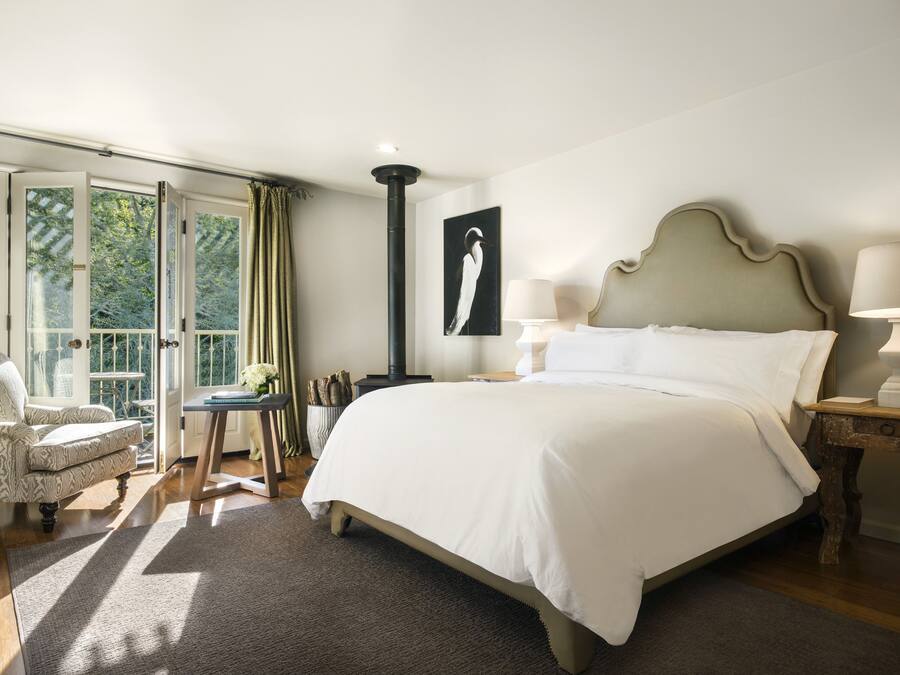 Een slaapkamer met een groot bed, een bureau, een stoel en uitzicht op de omgeving door een glazen deur.