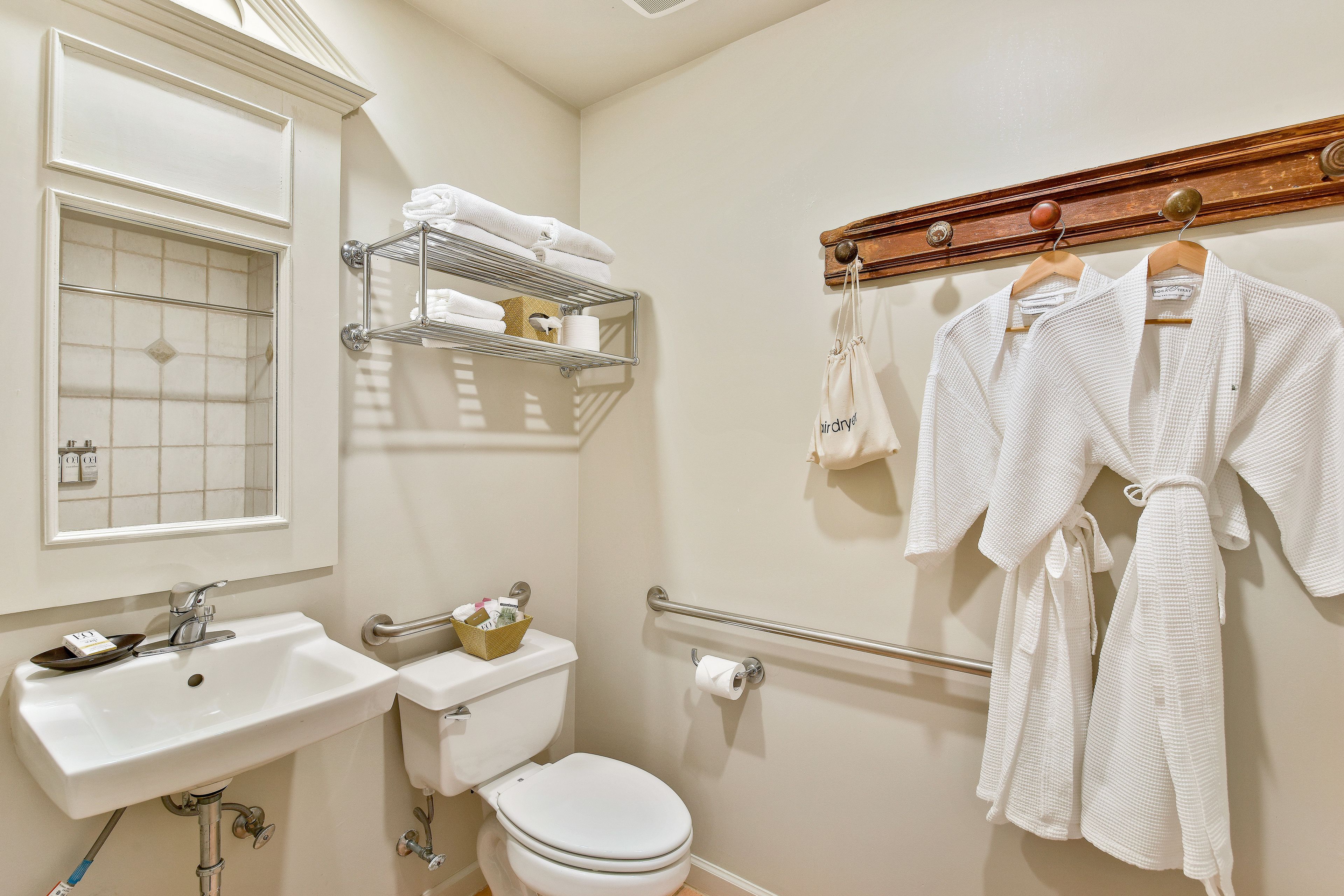 Une salle de bain avec un lavabo blanc, des toilettes et un porte-serviettes avec des peignoirs.