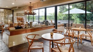 A café with a wooden counter, wicker chairs, and large windows offering a view of the outdoors. - Mill Valley Inn (Mill Valley)