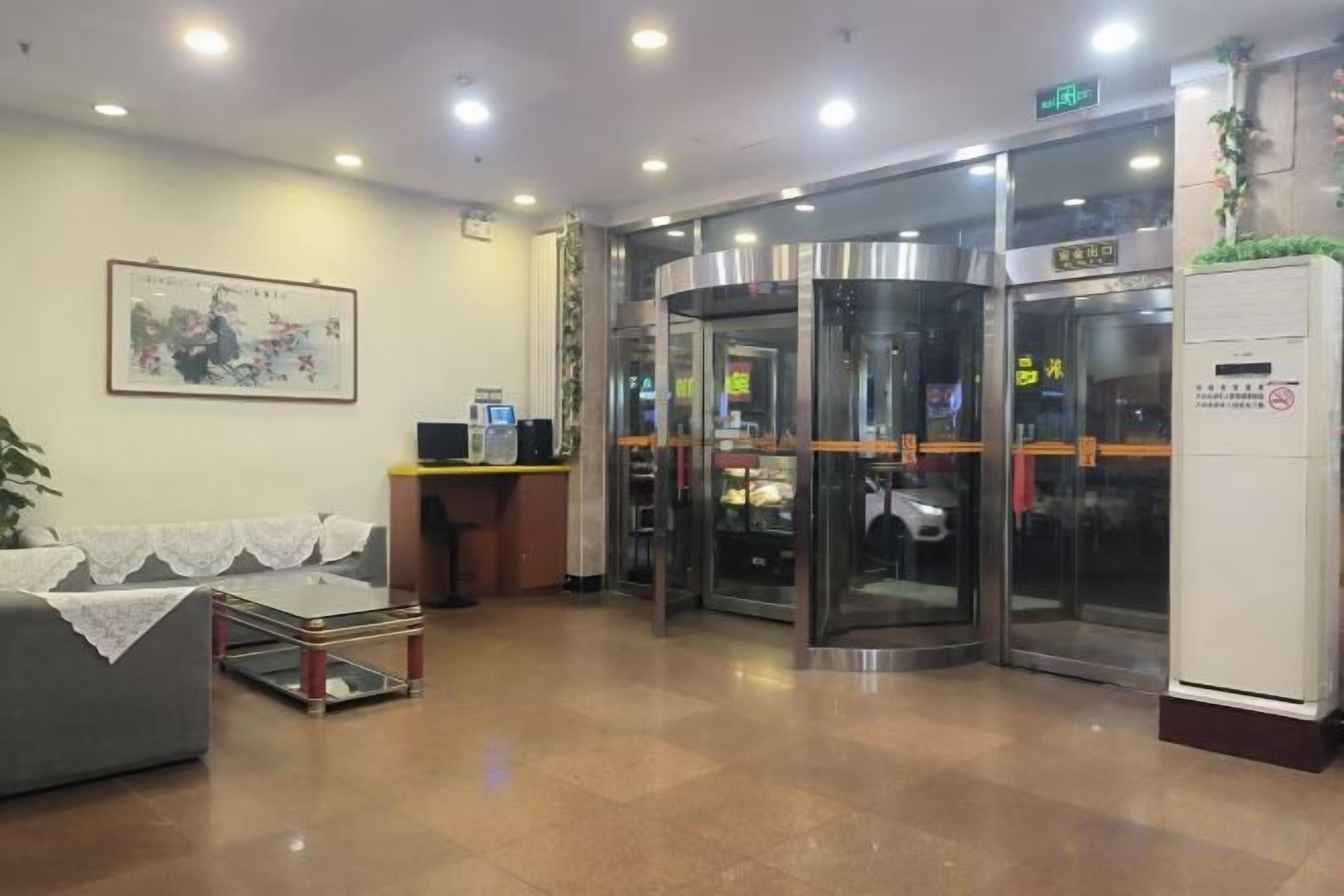 A hotel lobby with a reception desk, a seating area, and revolving doors.