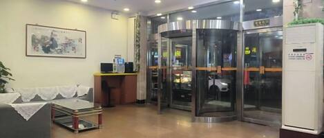 A hotel lobby with a reception desk, a seating area, and revolving doors.