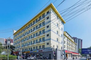Un hôtel  à plusieurs étages, doté d’une façade jaune, de nombreux balcons et de plusieurs boutiques situées au rez-de-chaussée.