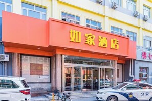 Un hôtel reconnaissable à son grand panneau orange, à son entrée en verre et à la voiture de police garée devant.