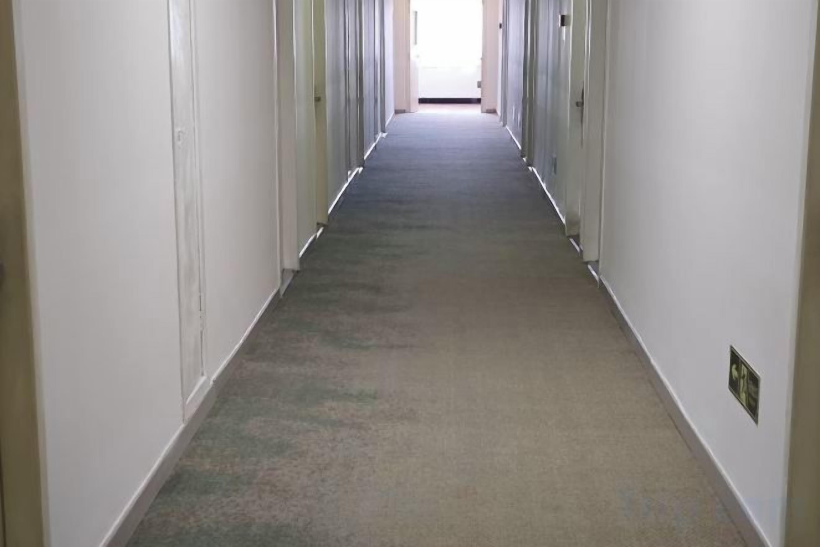 A long, narrow hallway with doors on both sides, leading to individual rooms.