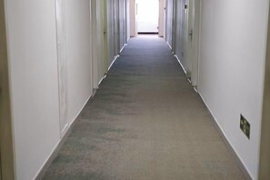 Un long couloir étroit, avec des portes des deux côtés, menant à des pièces individuelles.