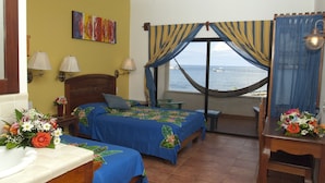 A room with two beds, a view of the sea, a hammock, and a bathroom with a sink and decorative tiles. - Sueno Del Mar Resort (Roatan)