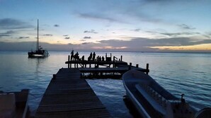 A wooden pier extending into calm waters with a boat docked at the end. - Sueno Del Mar Resort (Roatan)