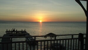 A sunset over the ocean with a pier and a gazebo. - Sueno Del Mar Resort (Roatan)